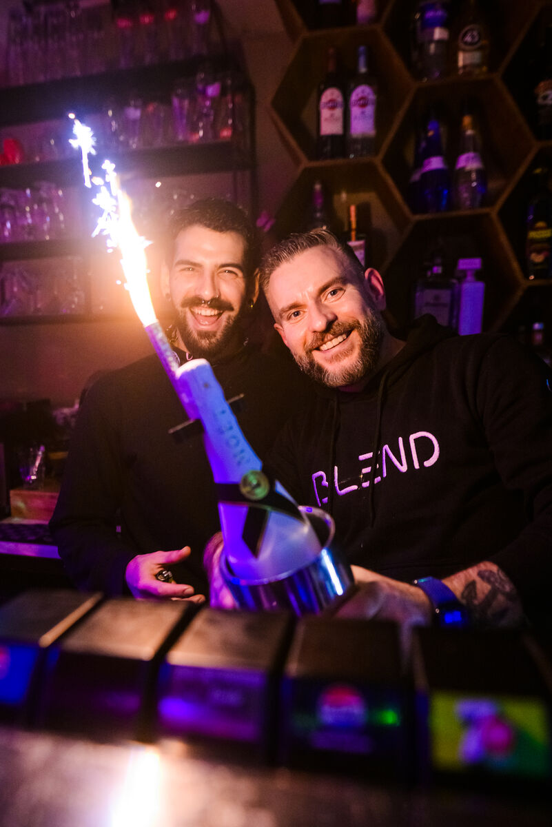 Two bartenders with a sparkling bottle behind the bar at Bar Blend Amsterdam