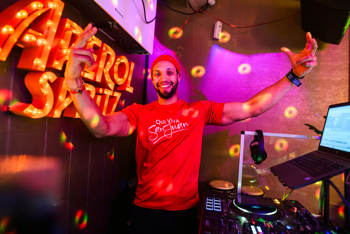 DJ with arms wide under the Aperol Spritz letters at Bar Blend Amsterdam