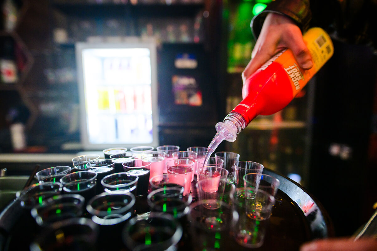 Bartender pouring a tray of pink shots at Bar Blend Amsterdam