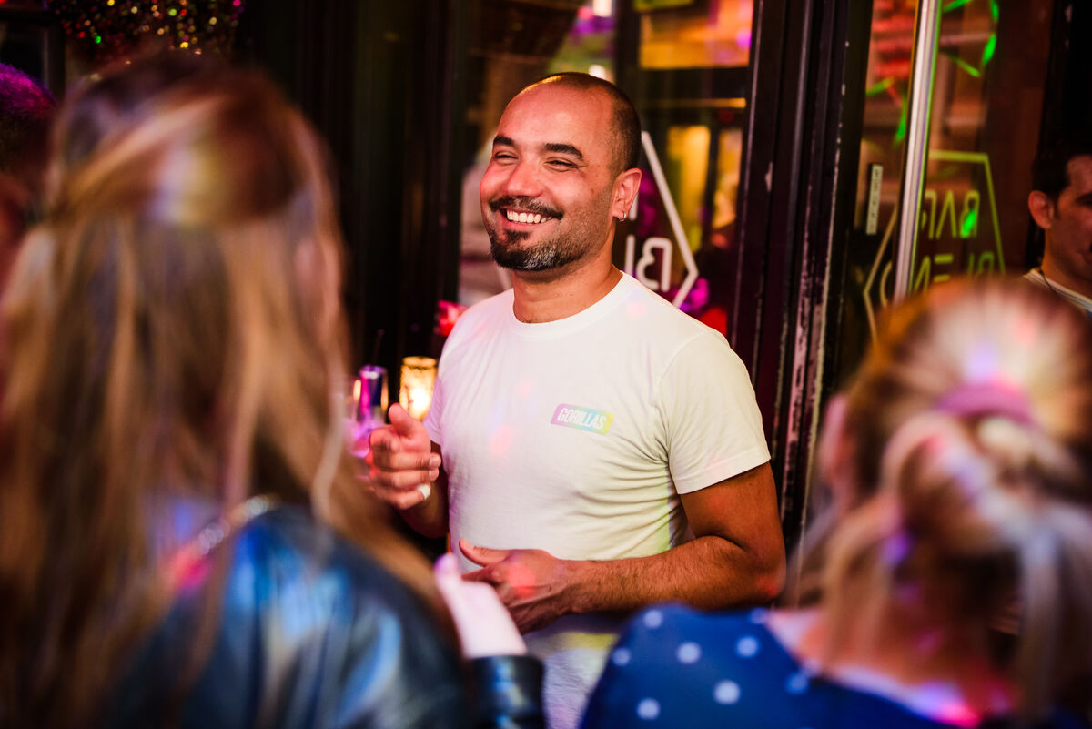 Smiling guest with a drink by the open front window of Bar Blend Amsterdam