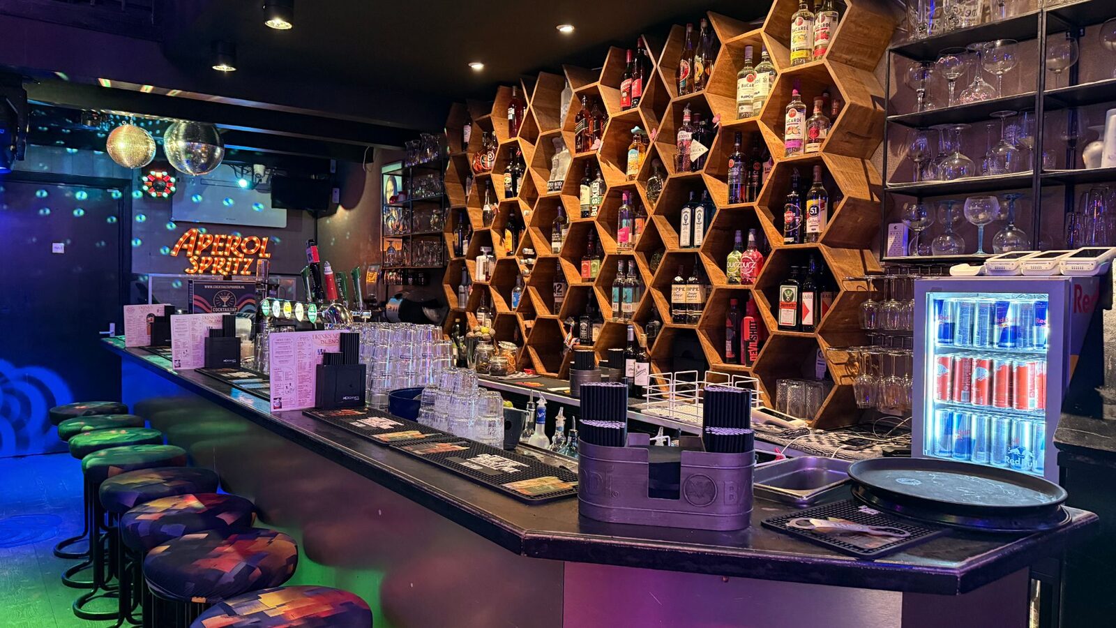 The bar at Bar Blend Amsterdam with honeycomb shelving, bar stools and an Aperol Spritz sign