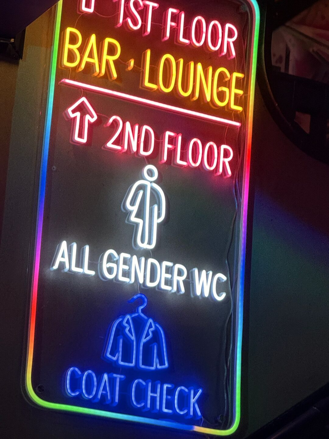 Neon sign at Bar Blend pointing to the bar and lounge on the first floor and the all-gender toilet and coat check on the second
