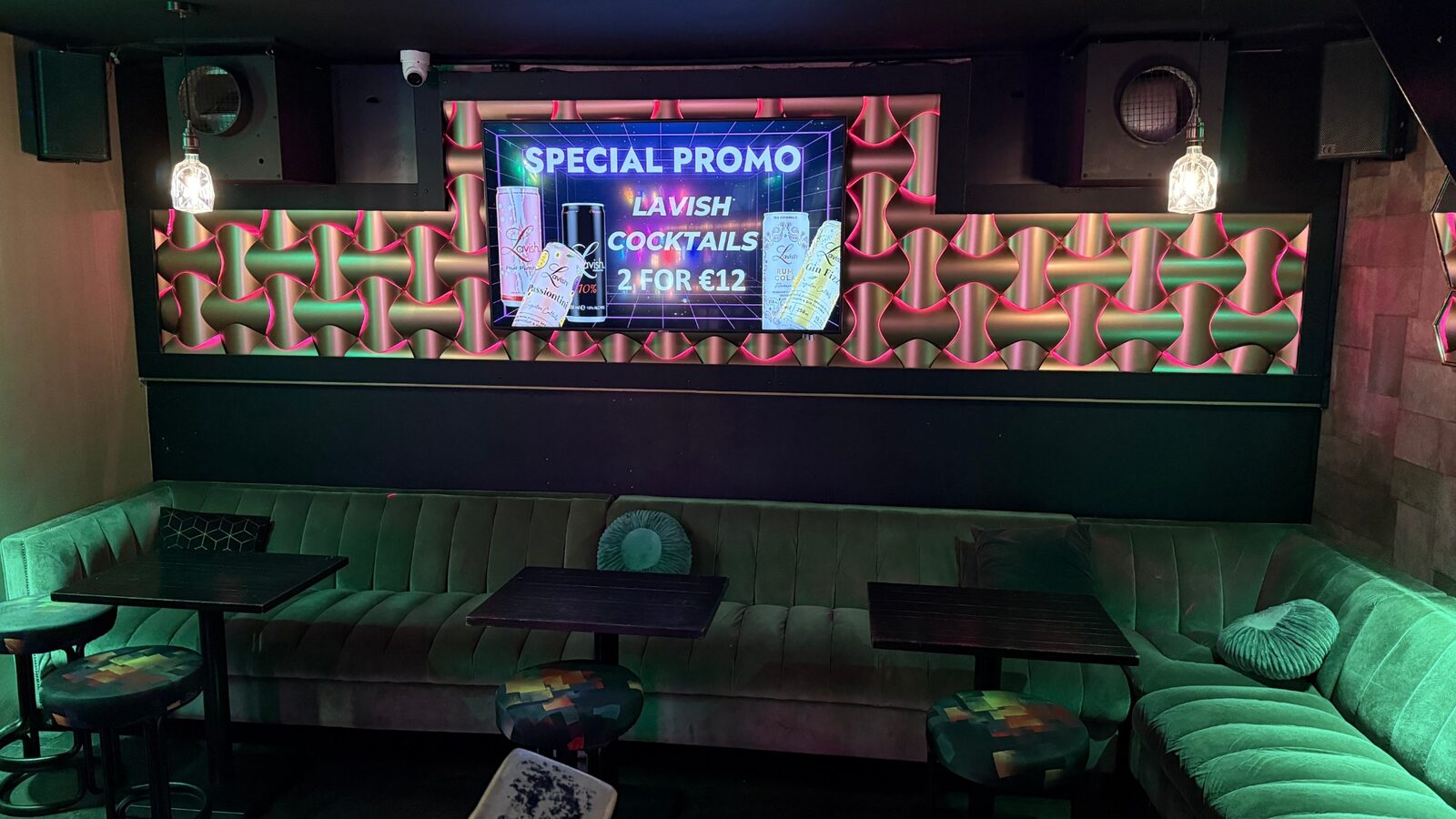 Green velvet lounge seating with dark tables and pixel-print stools at Bar Blend Amsterdam