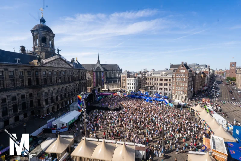 Aerial view of the packed Dam square during MainStage Pride Amsterdam, with the Royal Palace and the festival stage