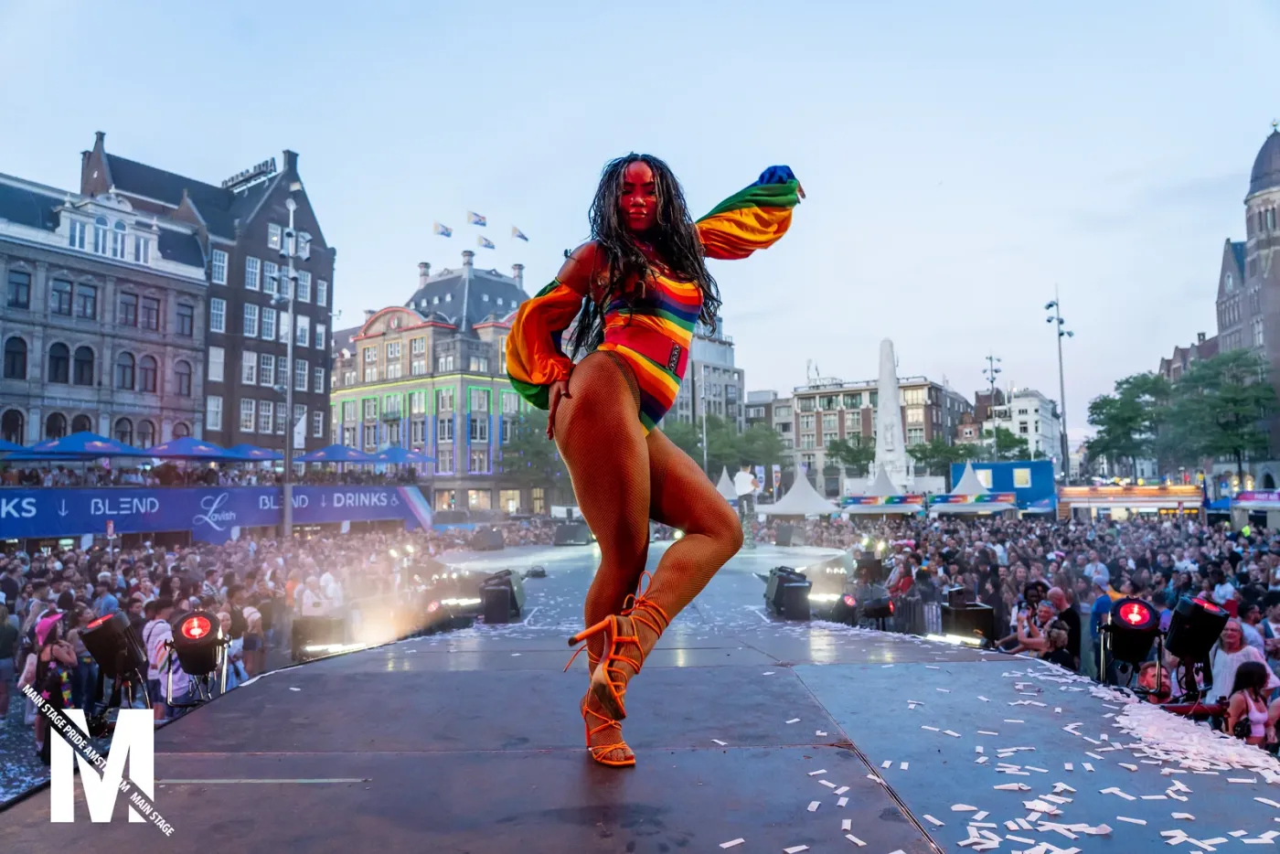 Dancer with a rainbow cape on the MainStage Pride runway amid confetti on Dam Square