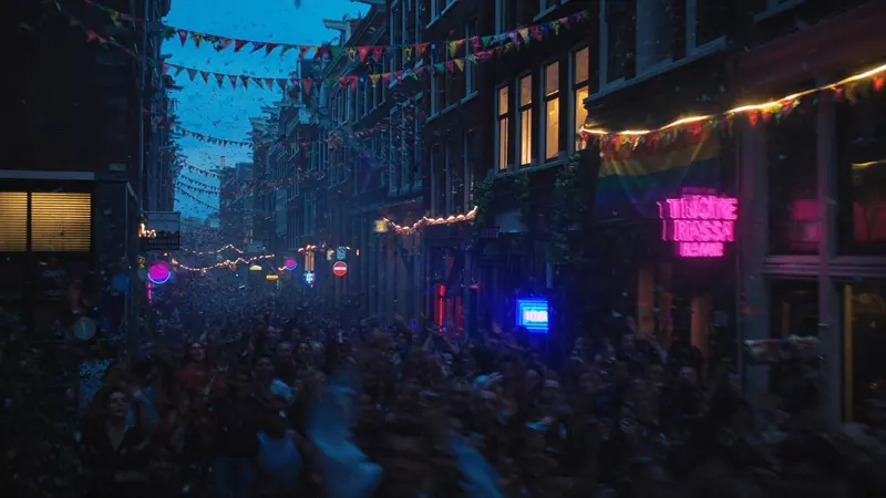 Pride street party on Reguliersdwarsstraat in Amsterdam with rainbow flags and neon bar lights
