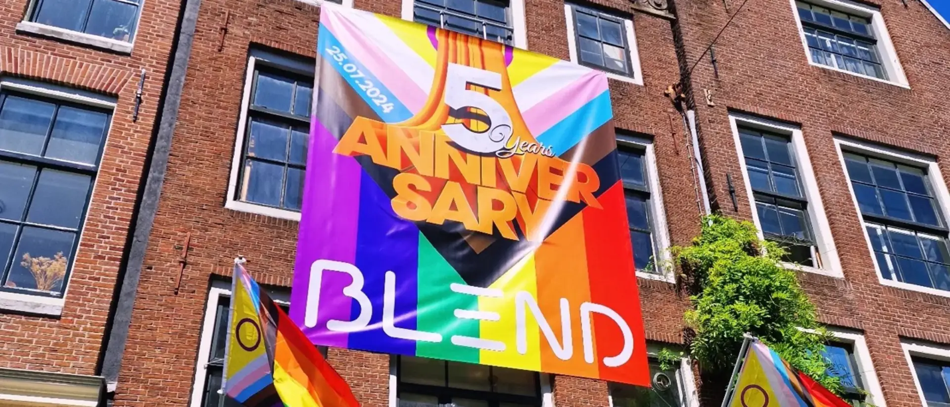 Gevel van Bar Blend met een regenboogbanier voor het vijfjarig bestaan en Progress Pride-vlaggen