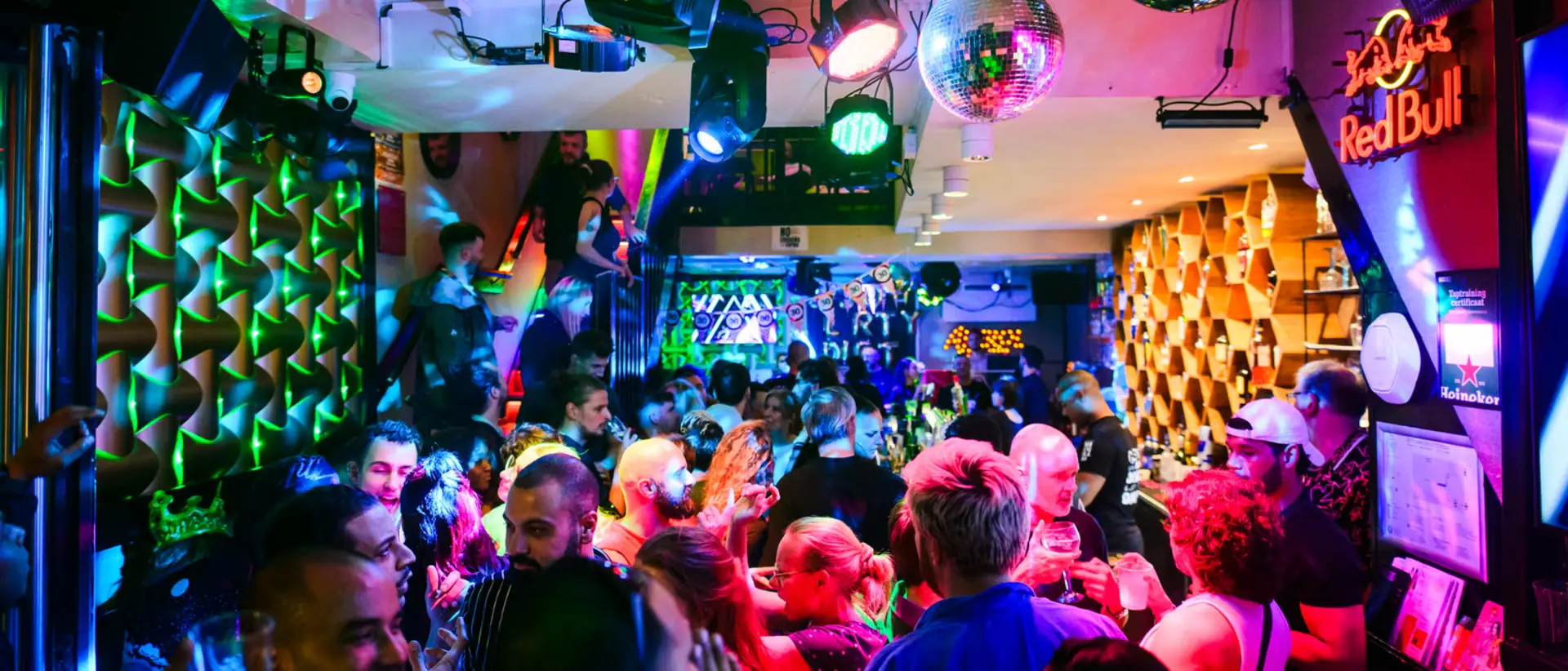Packed bar with a disco ball and green light on a busy night at Bar Blend