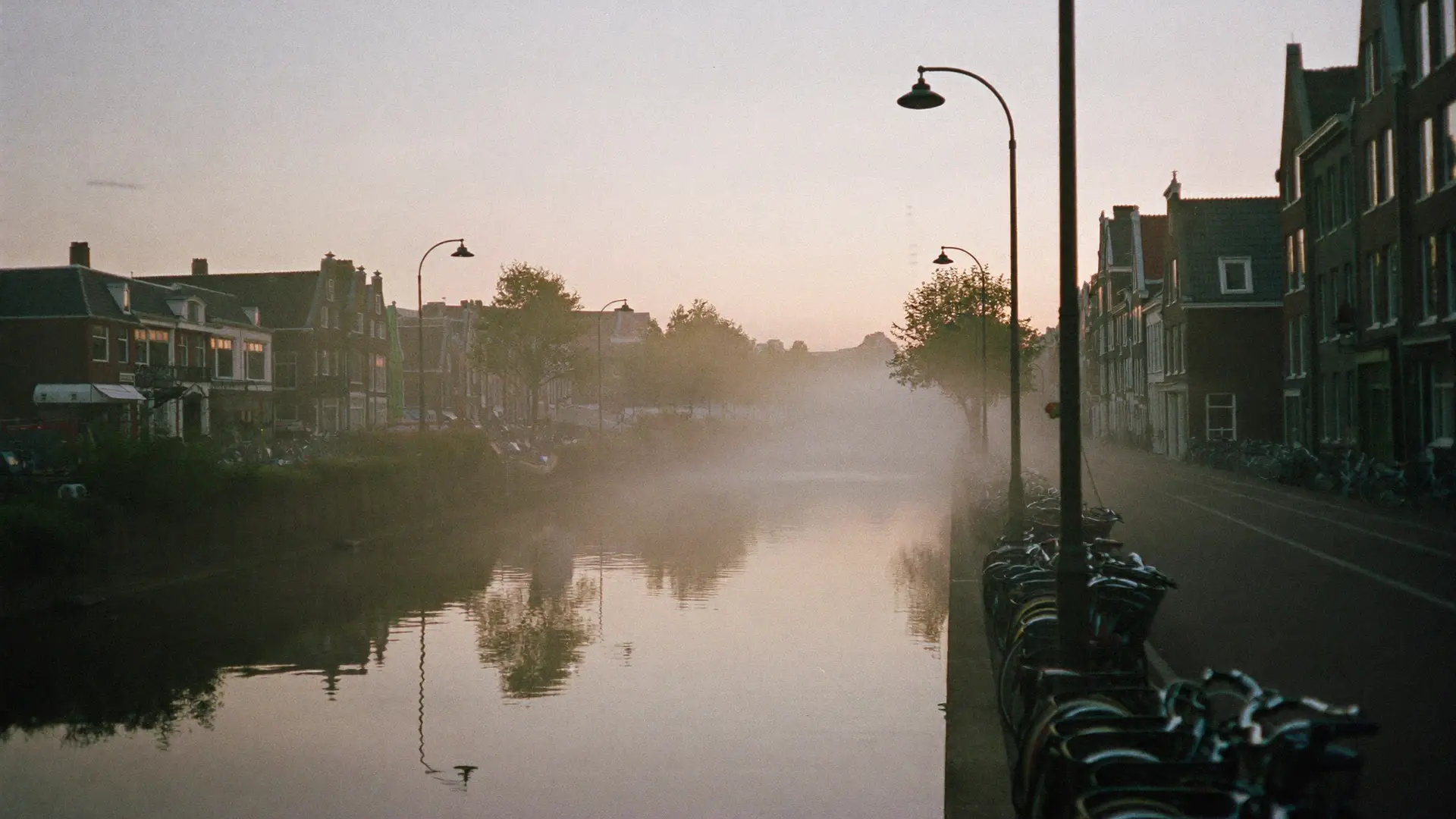 Een stille gracht bij zonsopkomst met mist op het water