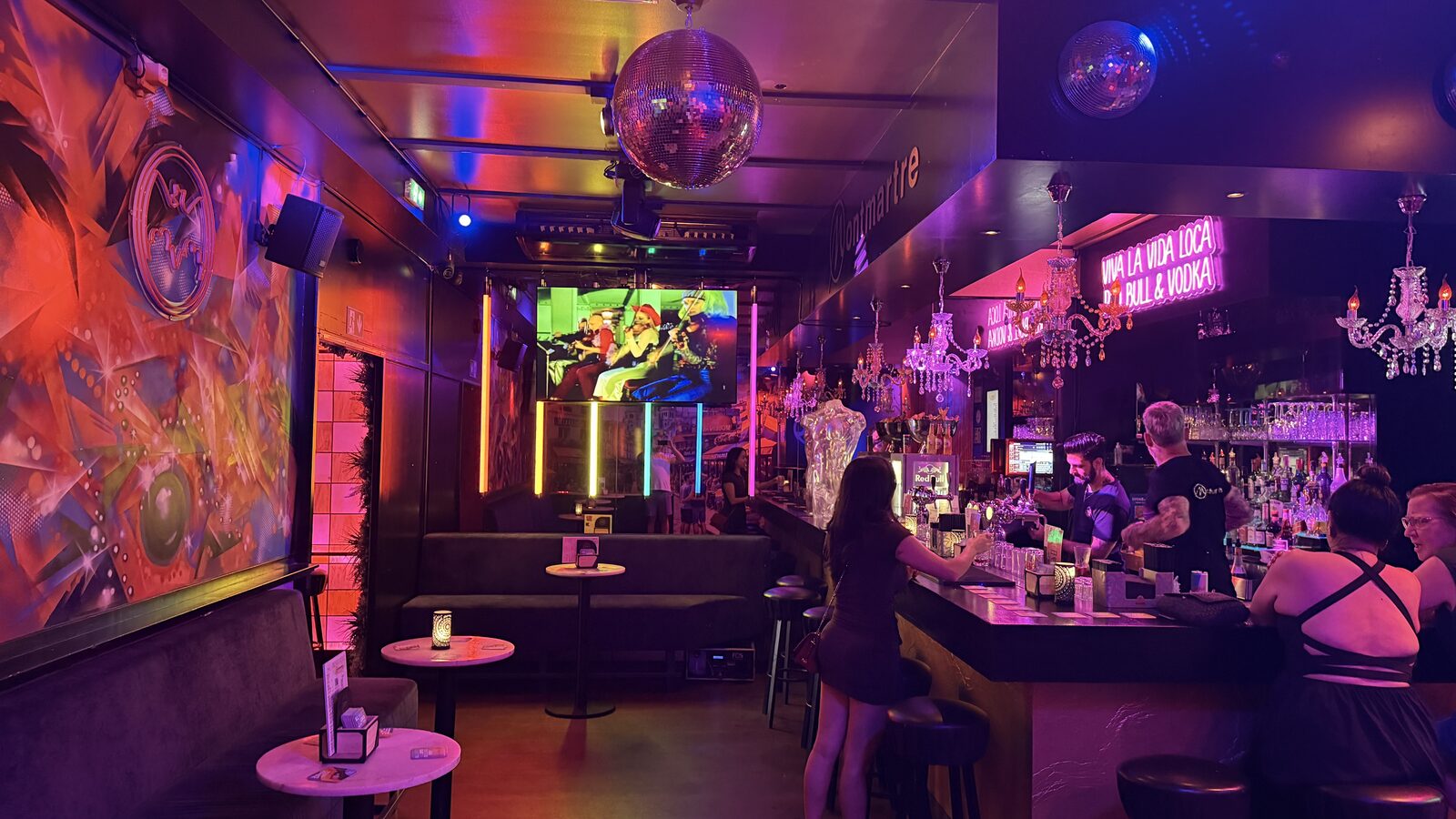 Disco ball, wall mural and karaoke screen above the gold-lit bar at Montmartre XL in Amsterdam